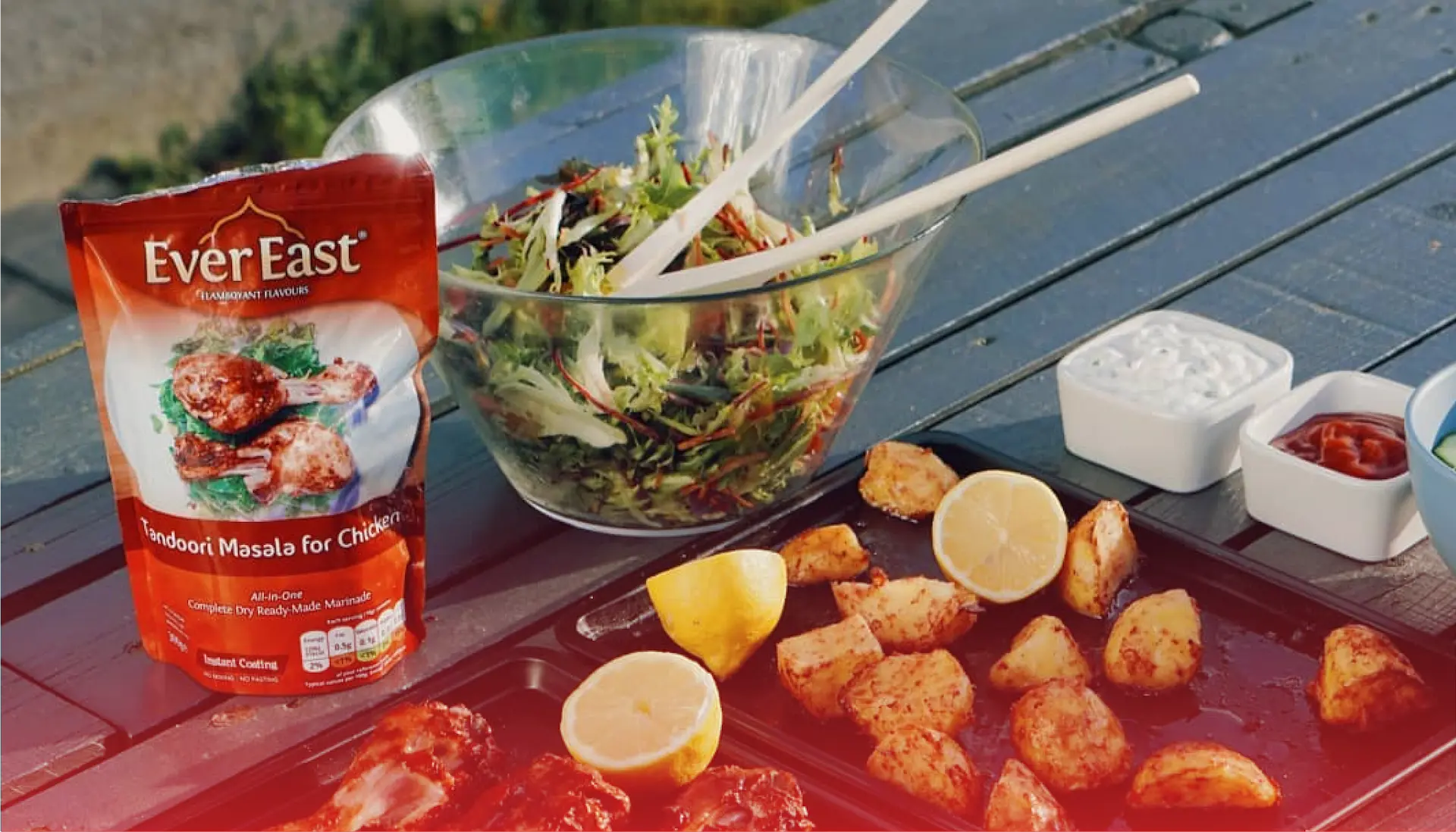 Editorial food spread showing EverEast marinade packets beside cooked tandoori chicken, la