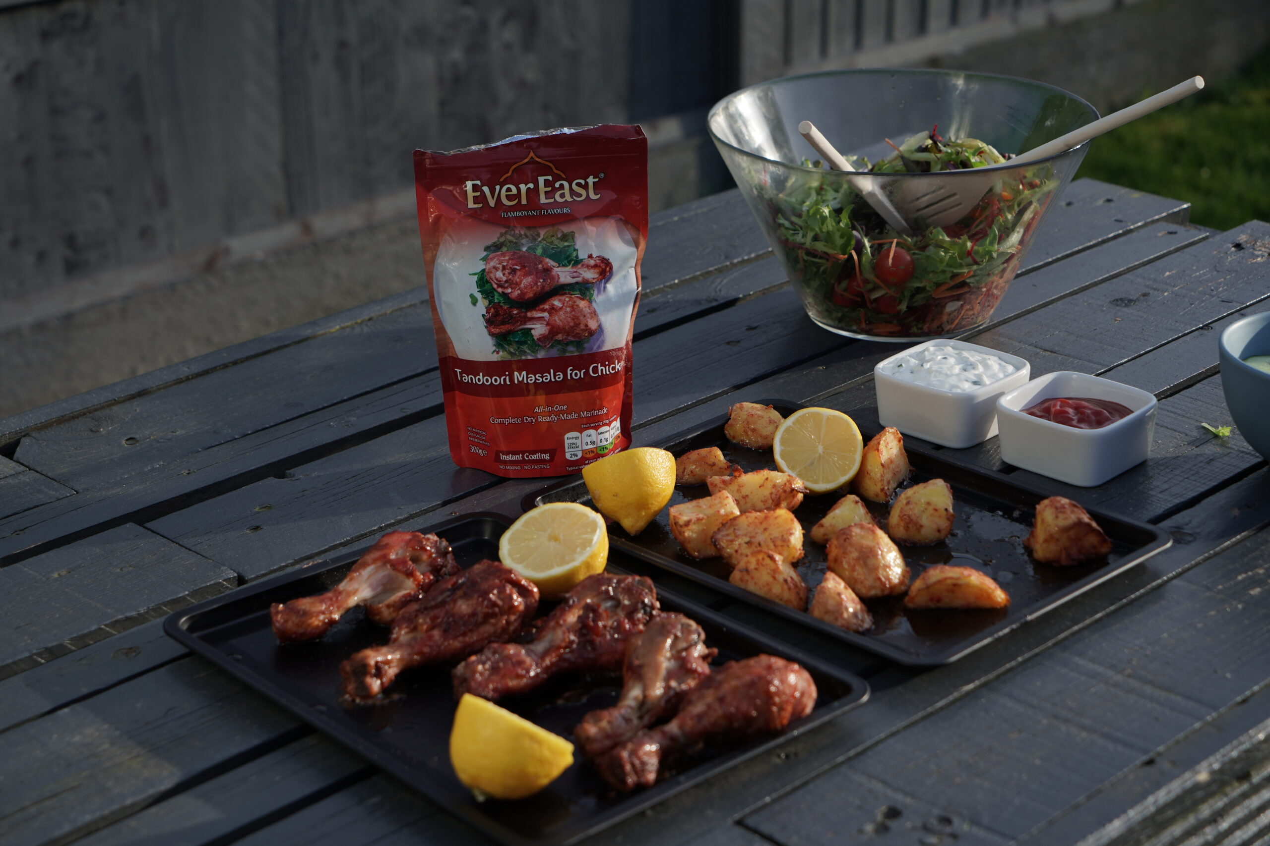 Ever East dry marinated chicken wings, lamb chops and fish skewers cooking on a UK garden